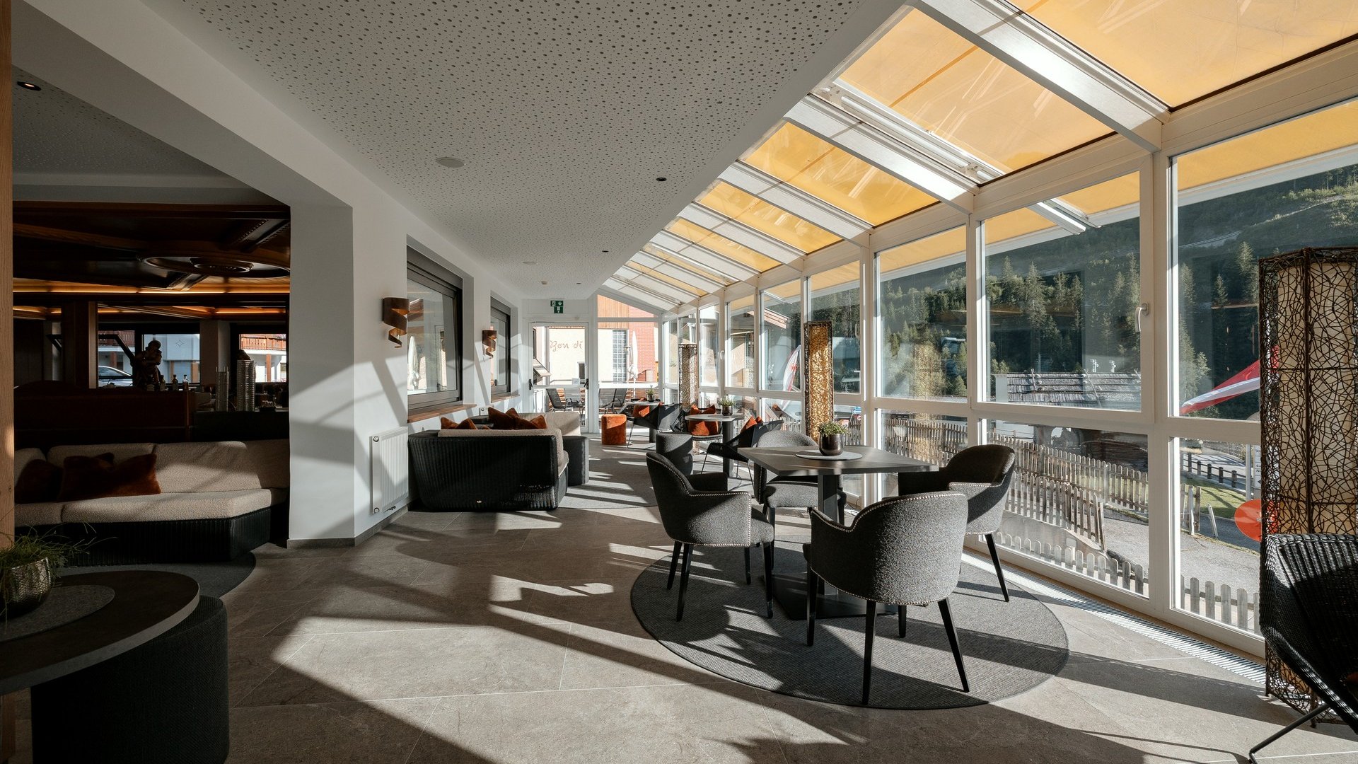 La tua vacanza in Val Gardena è qui Veranda luminosa con tavoli e sedie vista montagne