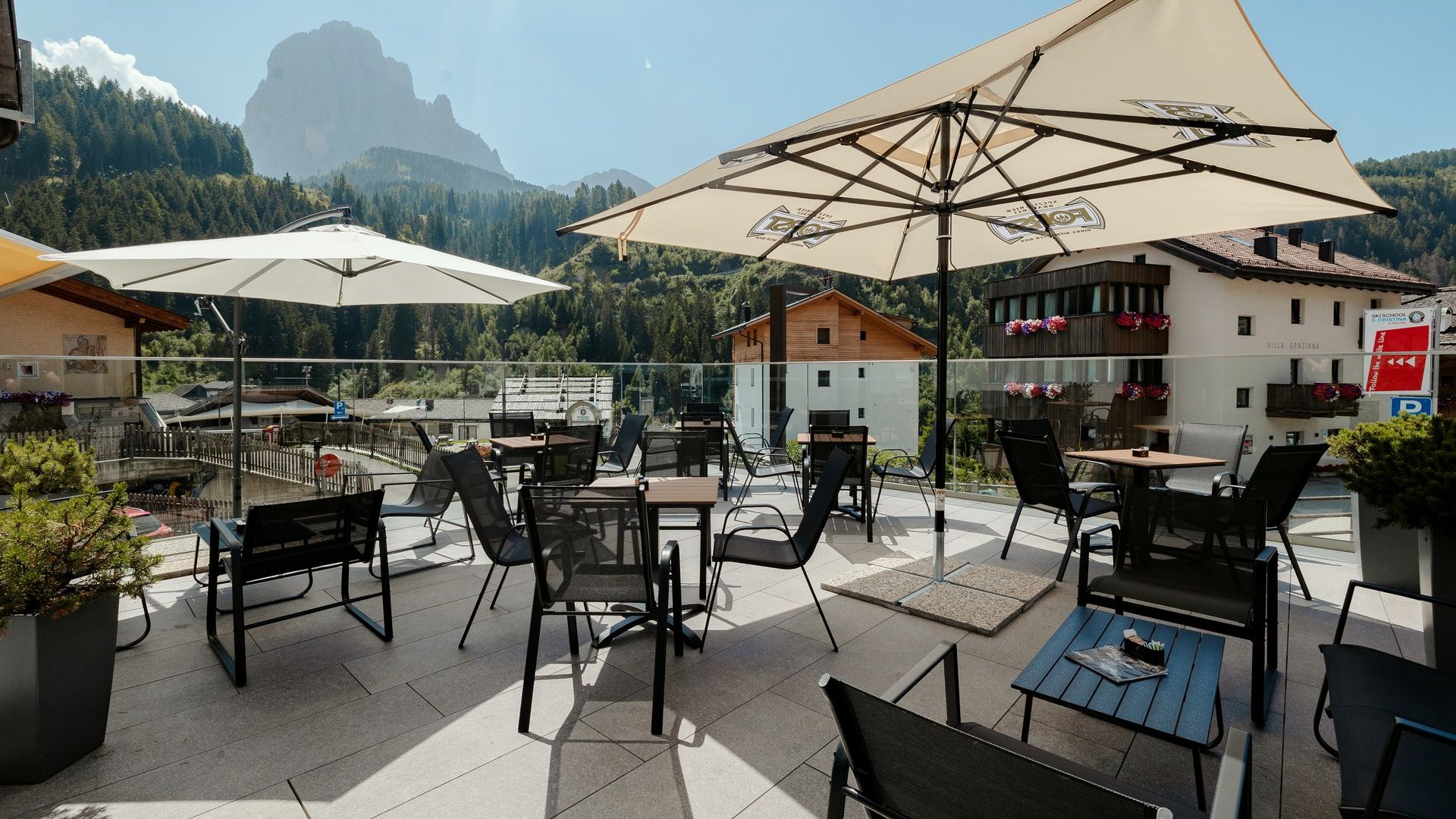 Inklusivleistungen deiner Gröden-Unterkunft Sonnige Terrasse mit Tischen und Stühlen in den Bergen