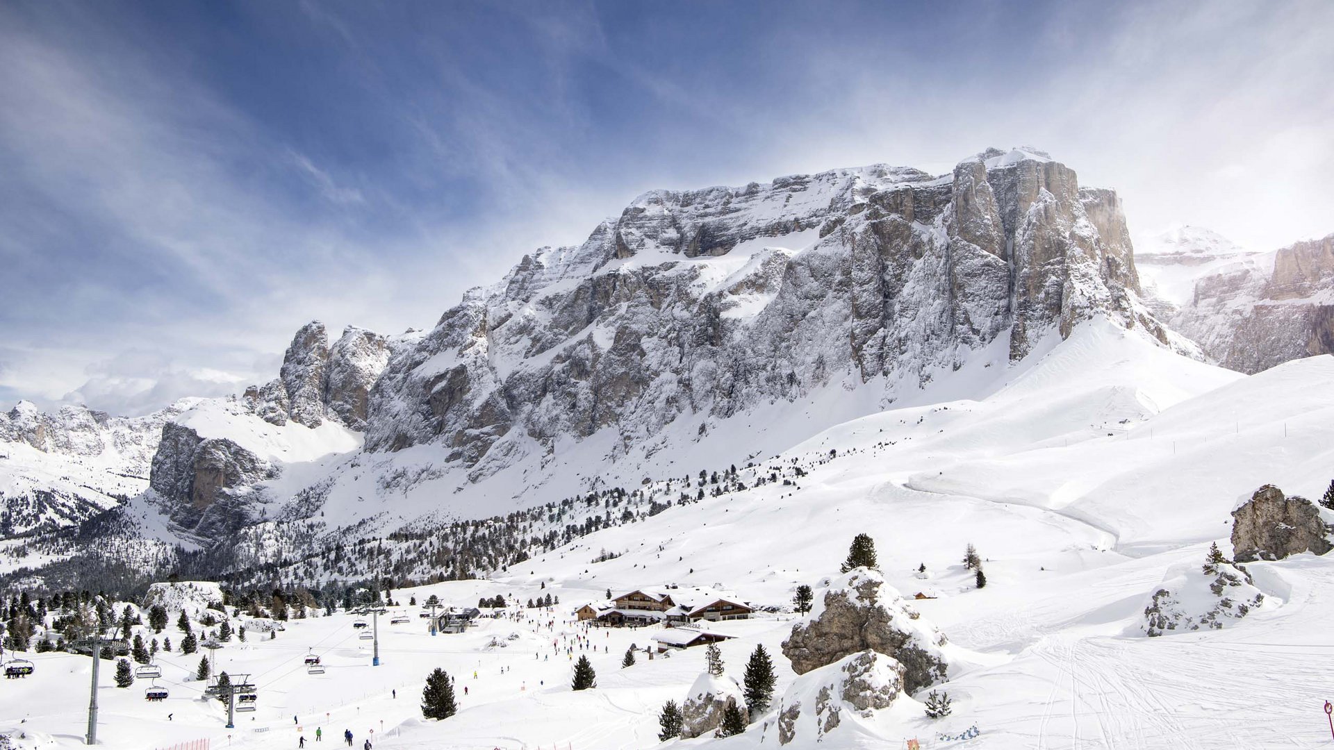Your hosts in the Dolomites. Hotels + 3 stars? Cristallo! Snow-covered mountains with ski lift, skiers, and blue sky