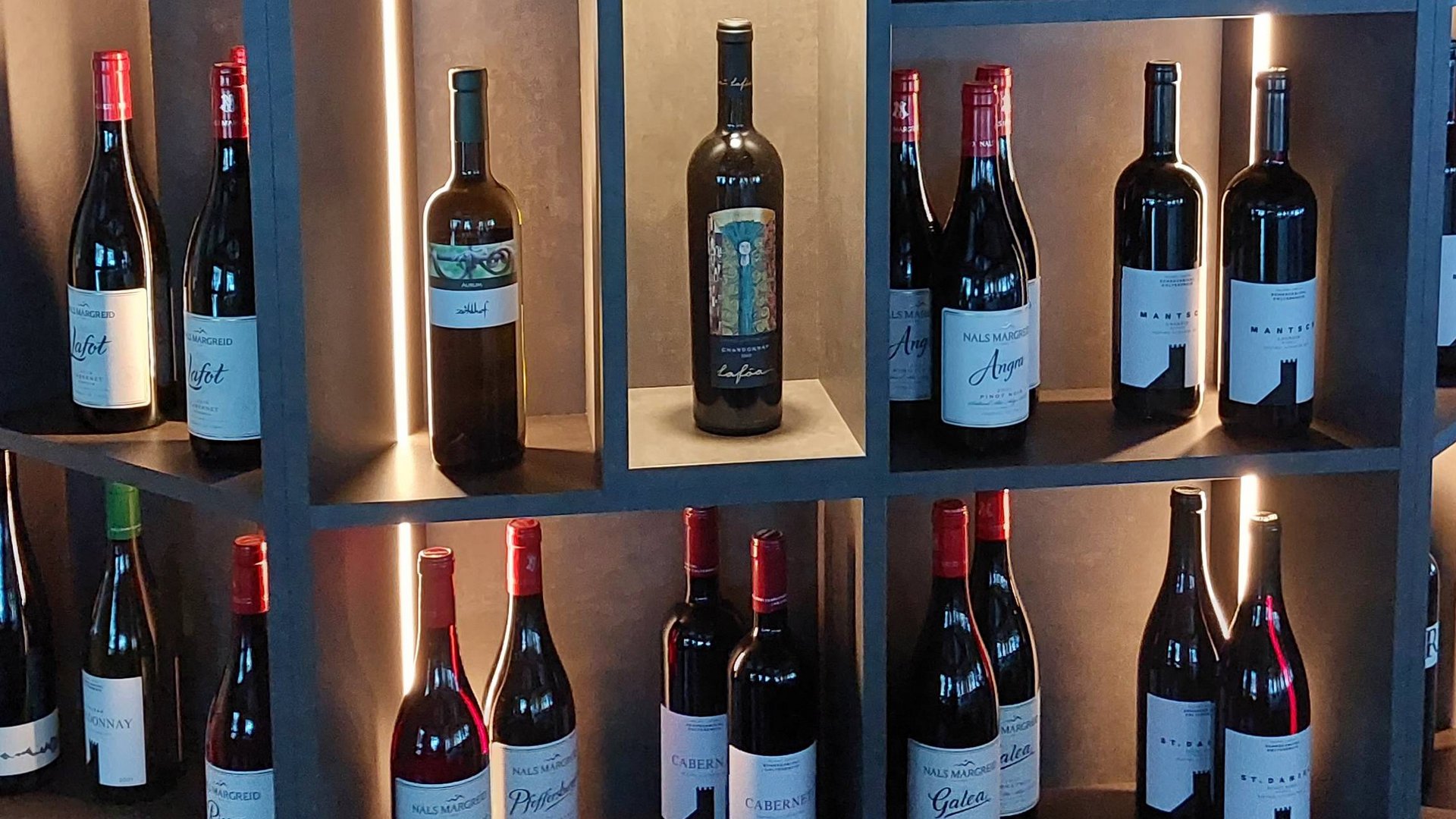 Cuisine at one of the top hotels in Grödnertal with 3 stars Wine bottles displayed in a modern illuminated wine rack