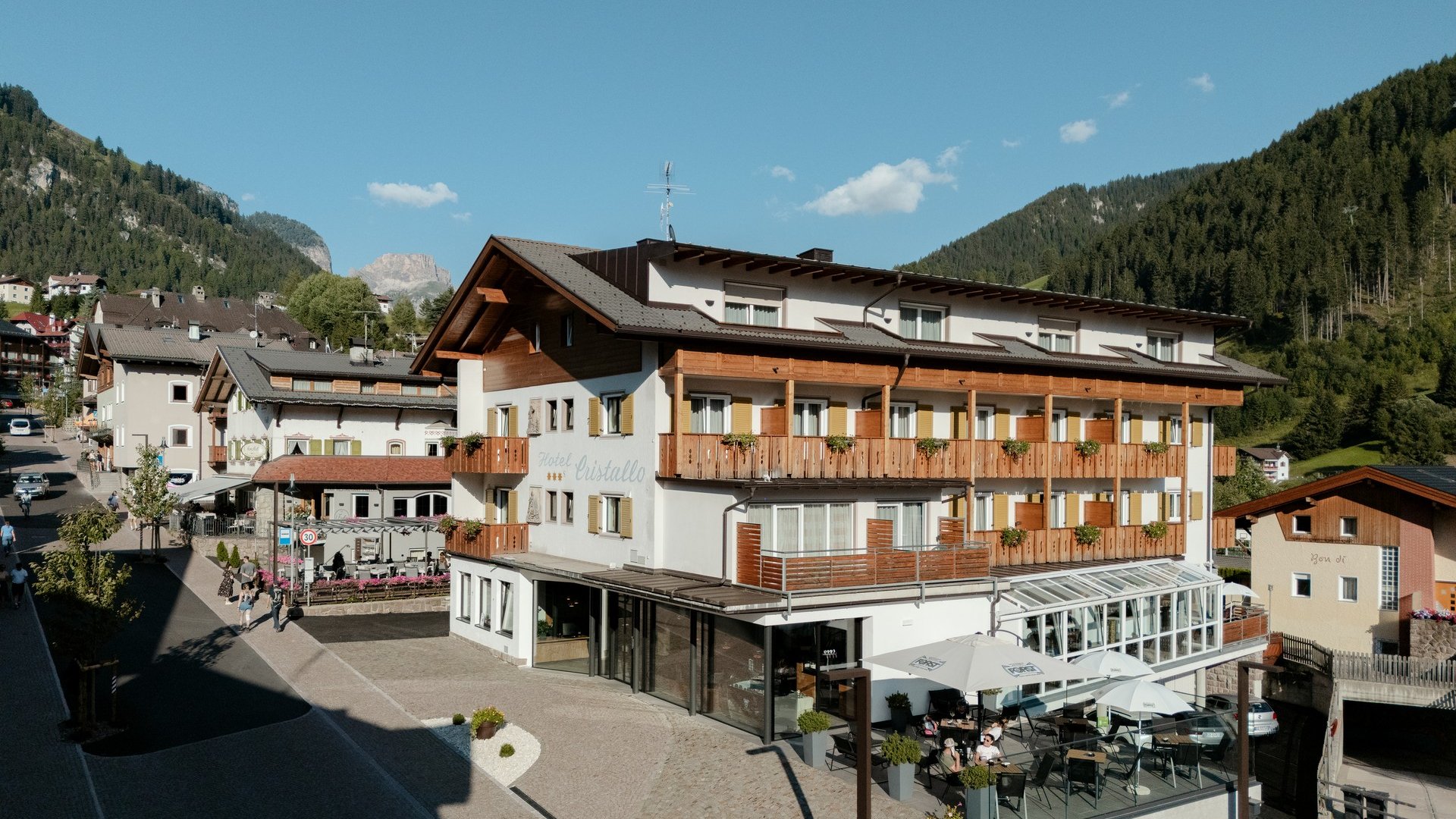 Hotelgebäude mit Terrasse und Bergen im Hintergrund unter blauem Himmel