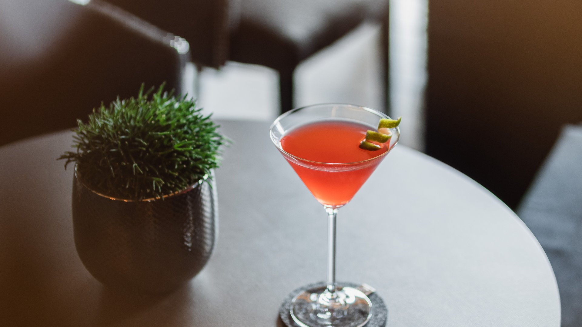 La tua vacanza in Val Gardena è qui Cocktail rosso in bicchiere da martini su tavolo rotondo con pianta