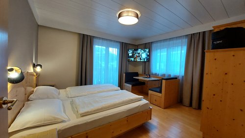 Hotel Cristallo: experience the Dolomites with these extras Cozy hotel room with double bed, seating area, and wall-mounted TV