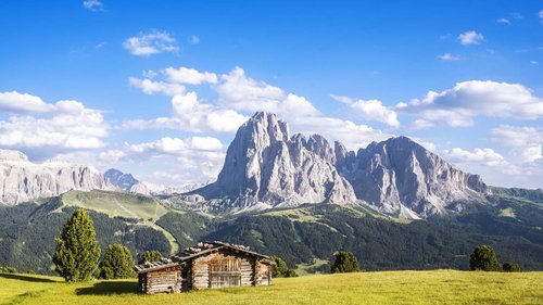 Hotel Cristallo: experience the Dolomites with these extras Wooden cabin on green meadow with mountain backdrop and blue sky