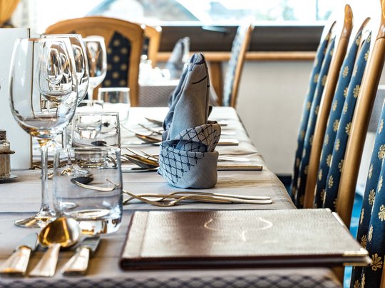 Deine Unterkunft in St. Christina im Grödnertal: Willkommen! Eleganter gedeckter Esstisch mit gefalteten Servietten und Glasgeschirr