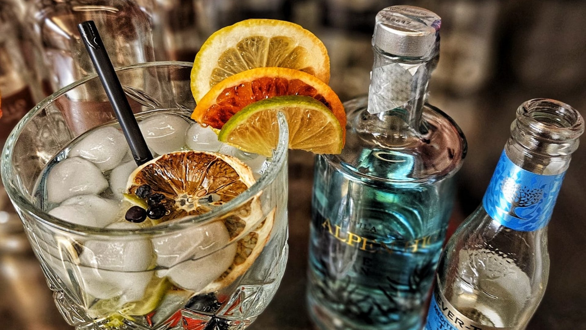 La tua vacanza in Val Gardena è qui Cocktail Gin Tonic con ghiaccio, fette di agrumi e due bottiglie sul tavolo