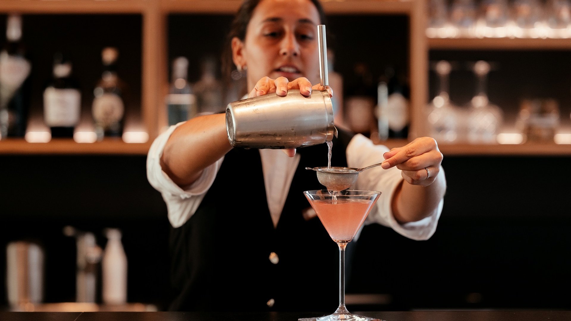 La tua vacanza in Val Gardena è qui Bartender versa un cocktail attraverso un colino in un bicchiere