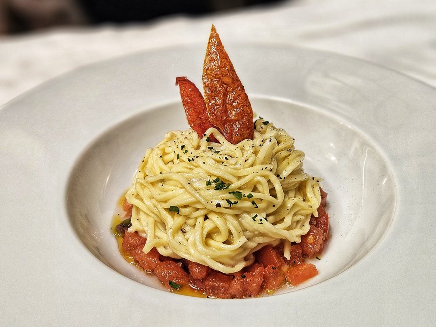 Cuisine at one of the top hotels in Grödnertal with 3 stars Pasta with diced tomatoes and pepper pieces on a white plate