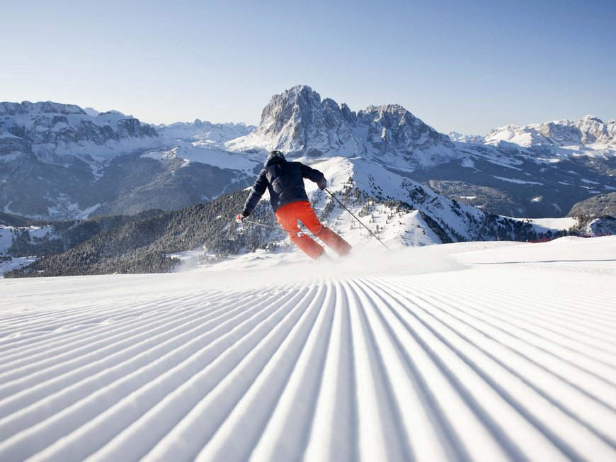 Vacanza in Val Gardena d’inverno Sciare su pista battuta con montagna sullo sfondo in una giornata limpida
