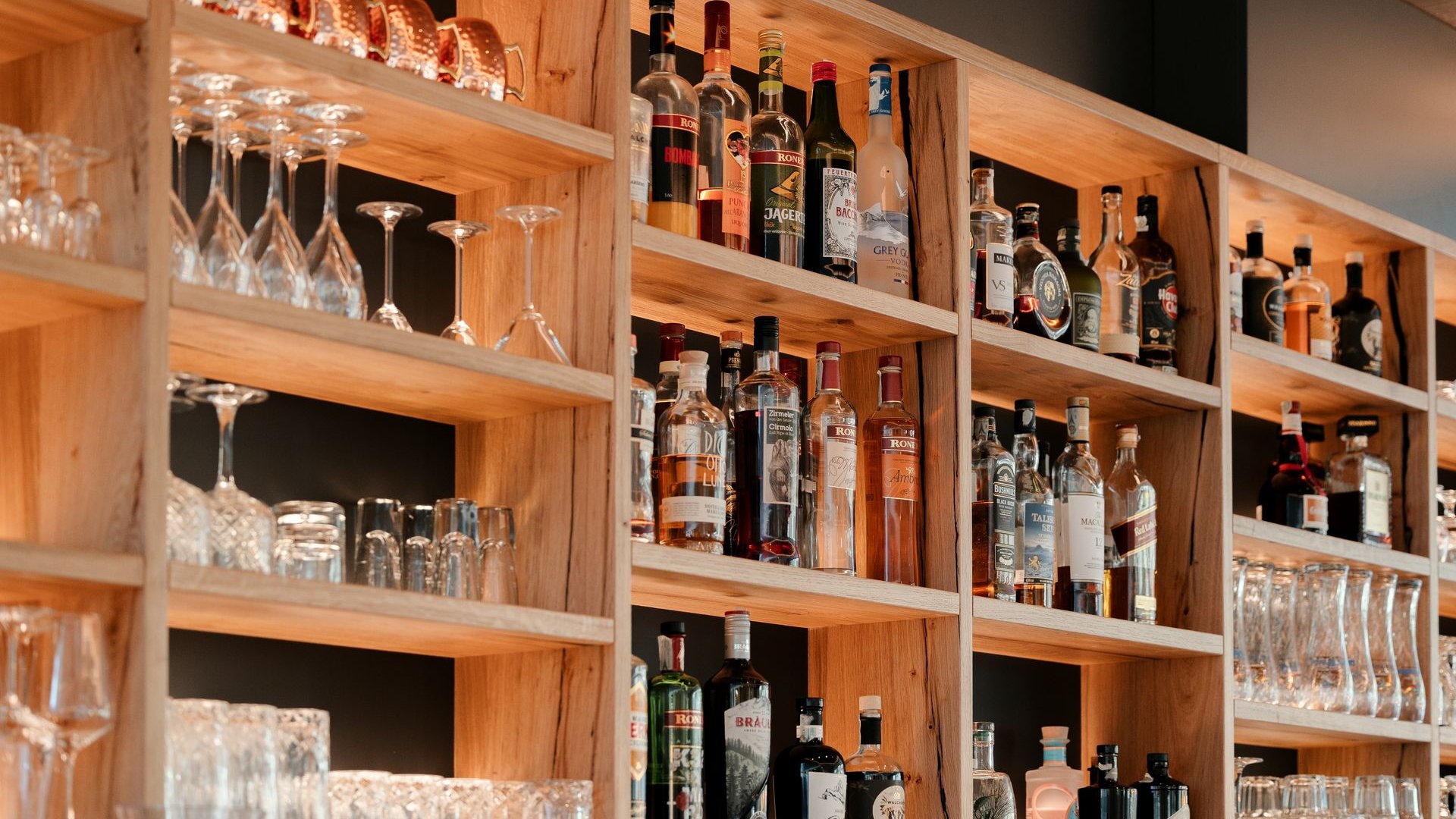 La tua vacanza in Val Gardena è qui Scaffale in legno con bottiglie di liquori e diversi tipi di bicchieri