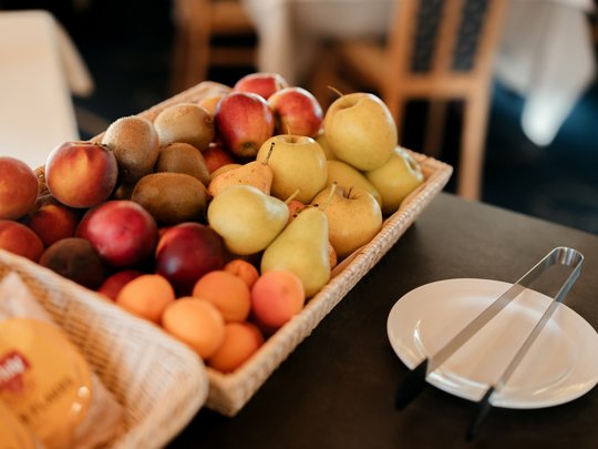 Cuisine at one of the top hotels in Grödnertal with 3 stars Basket of assorted fruits next to a plate with tongs