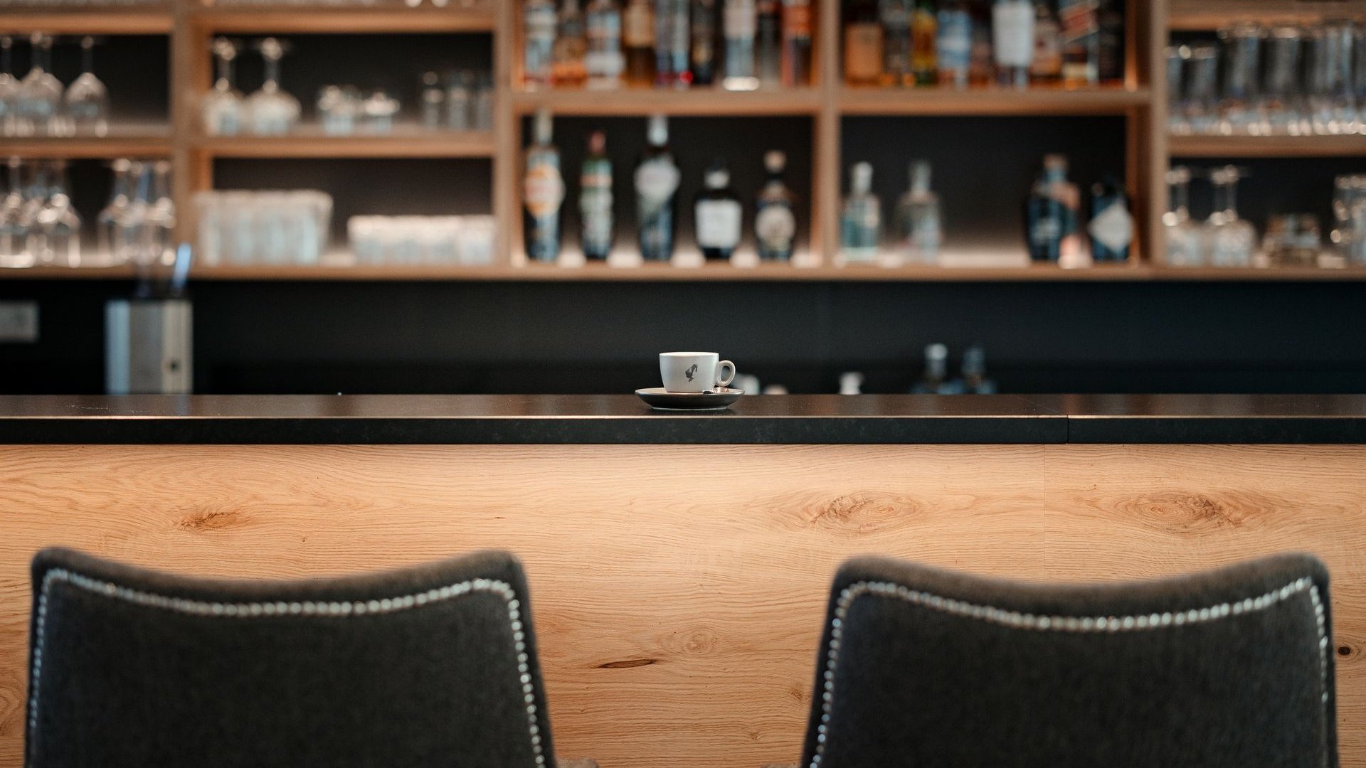 Inklusivleistungen deiner Gröden-Unterkunft Kaffeetasse auf der Bar an einem gemütlichen Ort mit Regal und Glaswaren im Hintergrund