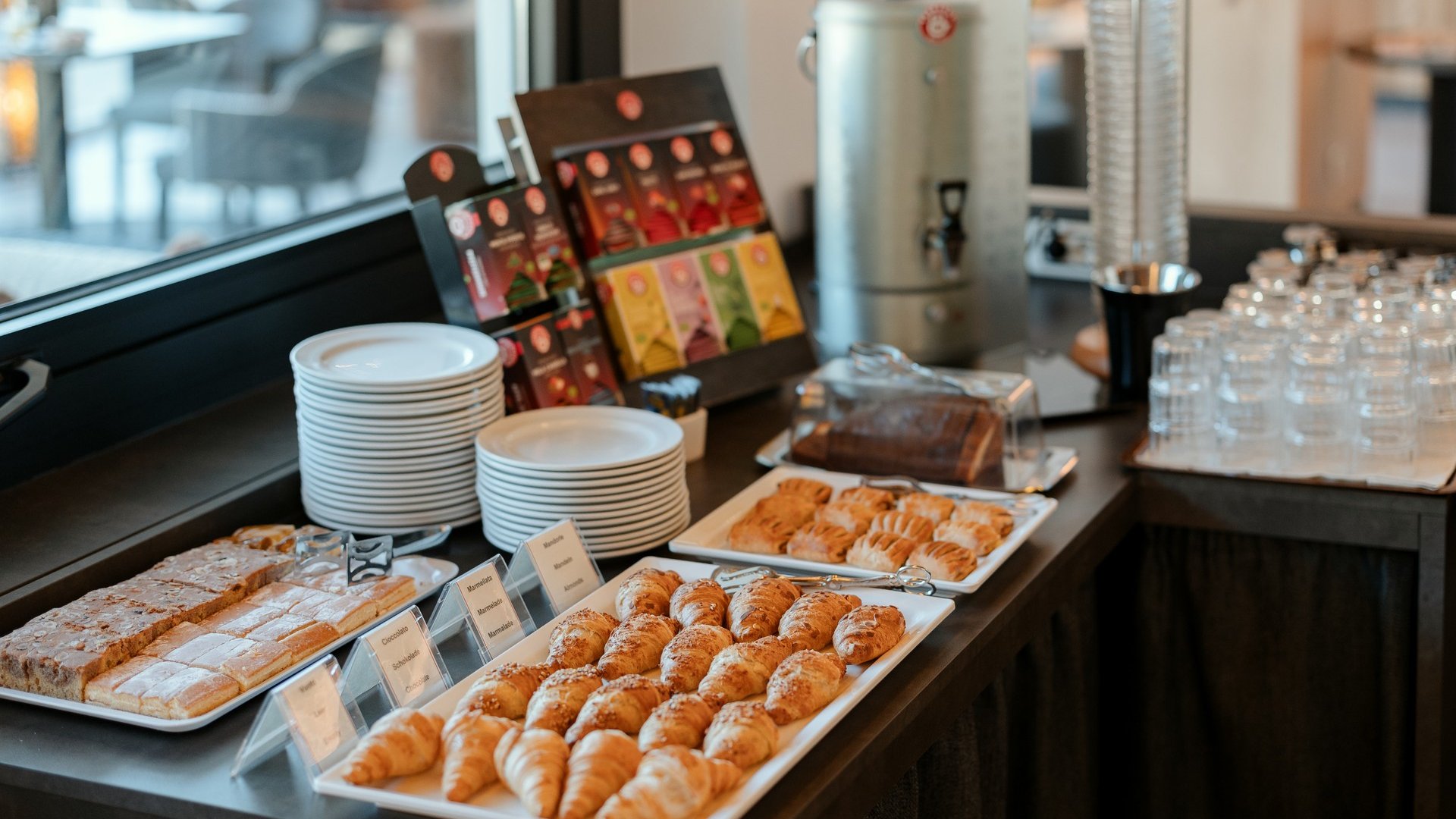 Cuisine at one of the top hotels in Grödnertal with 3 stars Buffet with croissants, pastries, tea bags, glasses, and plates