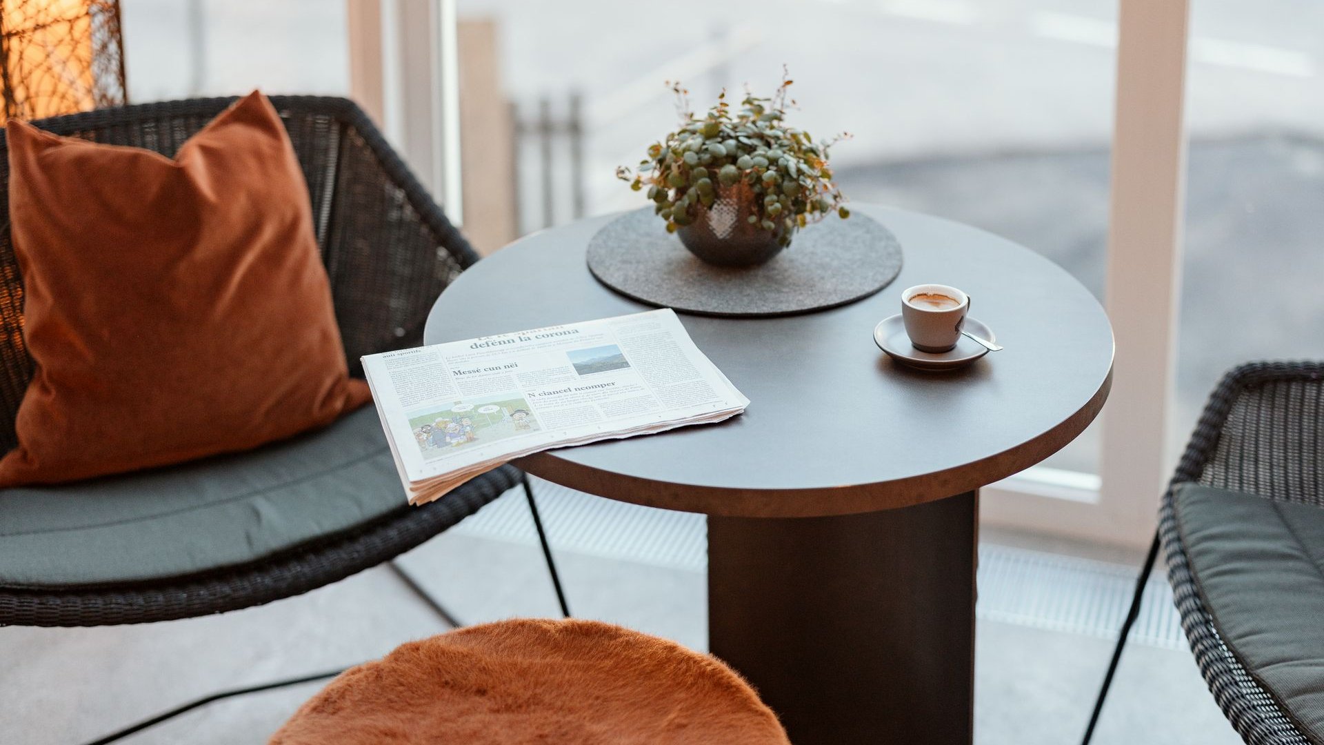 La tua vacanza in Val Gardena è qui Tavolo accogliente con giornale, tazza di caffè e pianta vicino alle sedie
