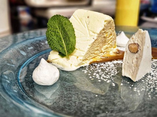 Cuisine at one of the top hotels in Grödnertal with 3 stars Creamy dessert with mint leaf and powdered sugar on glass plate