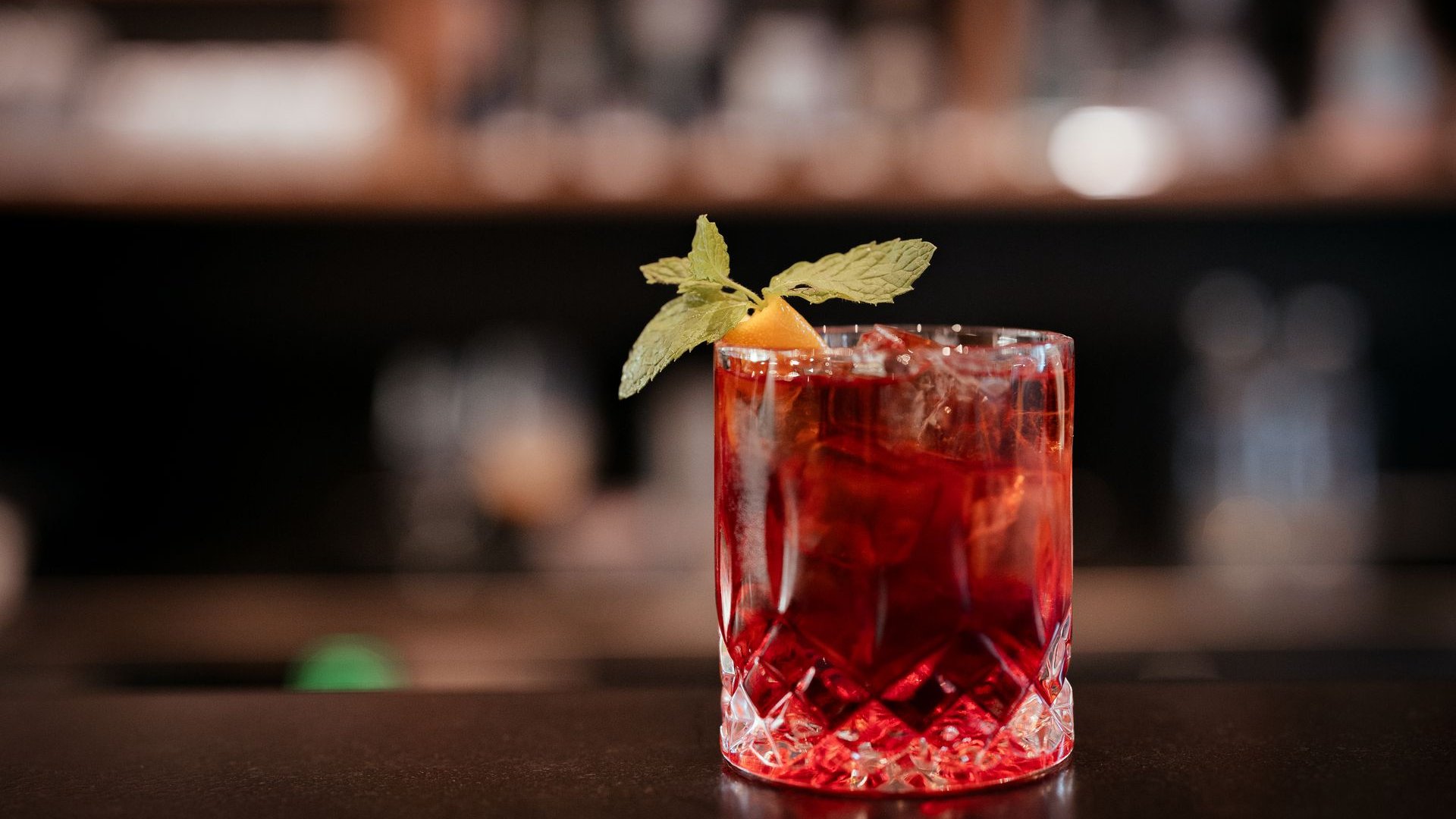 La tua vacanza in Val Gardena è qui Cocktail rosso in bicchiere di cristallo con foglia di menta e scorza d'arancia