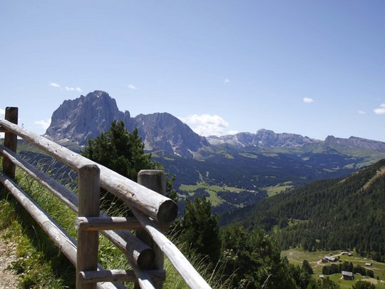 Dolomiten + Wandern + Hotel Cristallo = hallo Sommer! Gebirgstal mit Holzzaun im Vordergrund und wolkenlosem Himmel