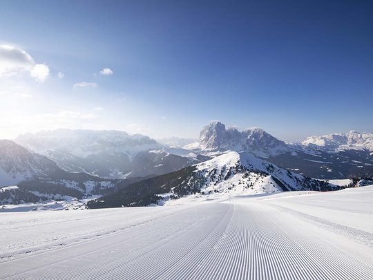Vacanza in Val Gardena d’inverno Pista da sci battuta con montagne innevate e cielo azzurro limpido