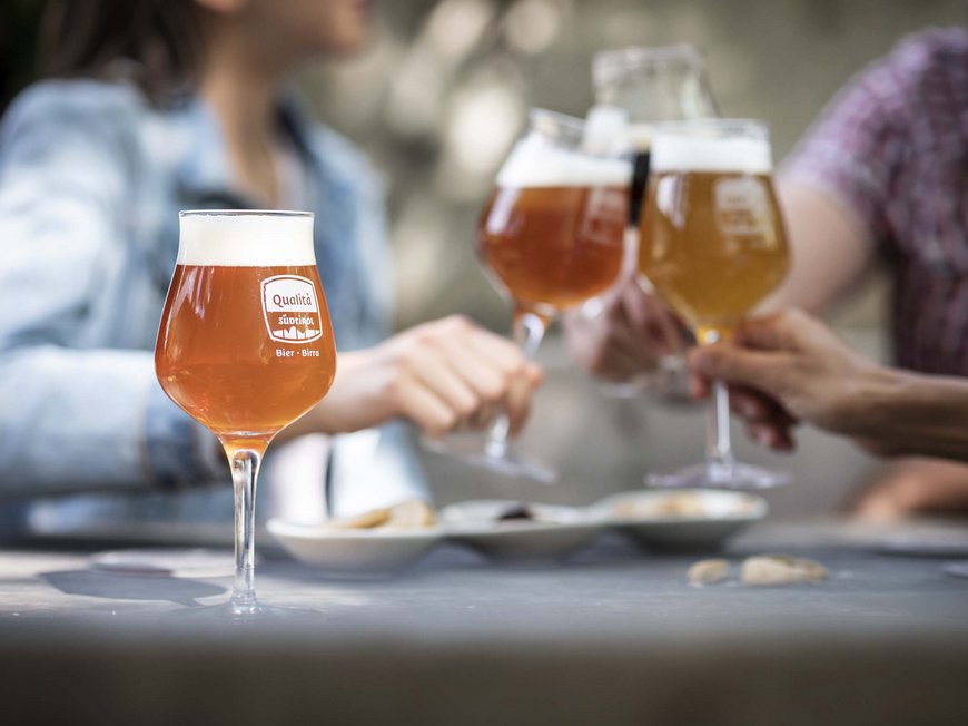 La tua vacanza in Val Gardena è qui Bicchieri di birra e persone che brindano a un tavolo