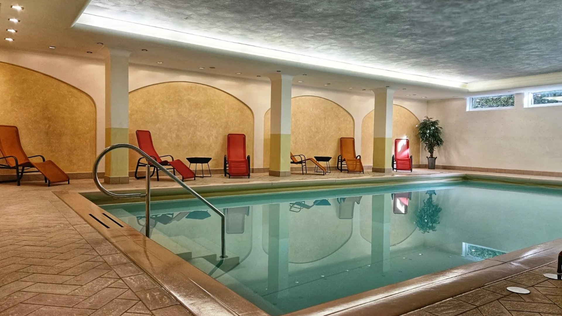 Südtirol-Hotel mit Pool (3 Sterne) gesucht? Hier ist es! Innenpool mit Liegestühlen und Pflanzen in einem modernen Wellnessbereich