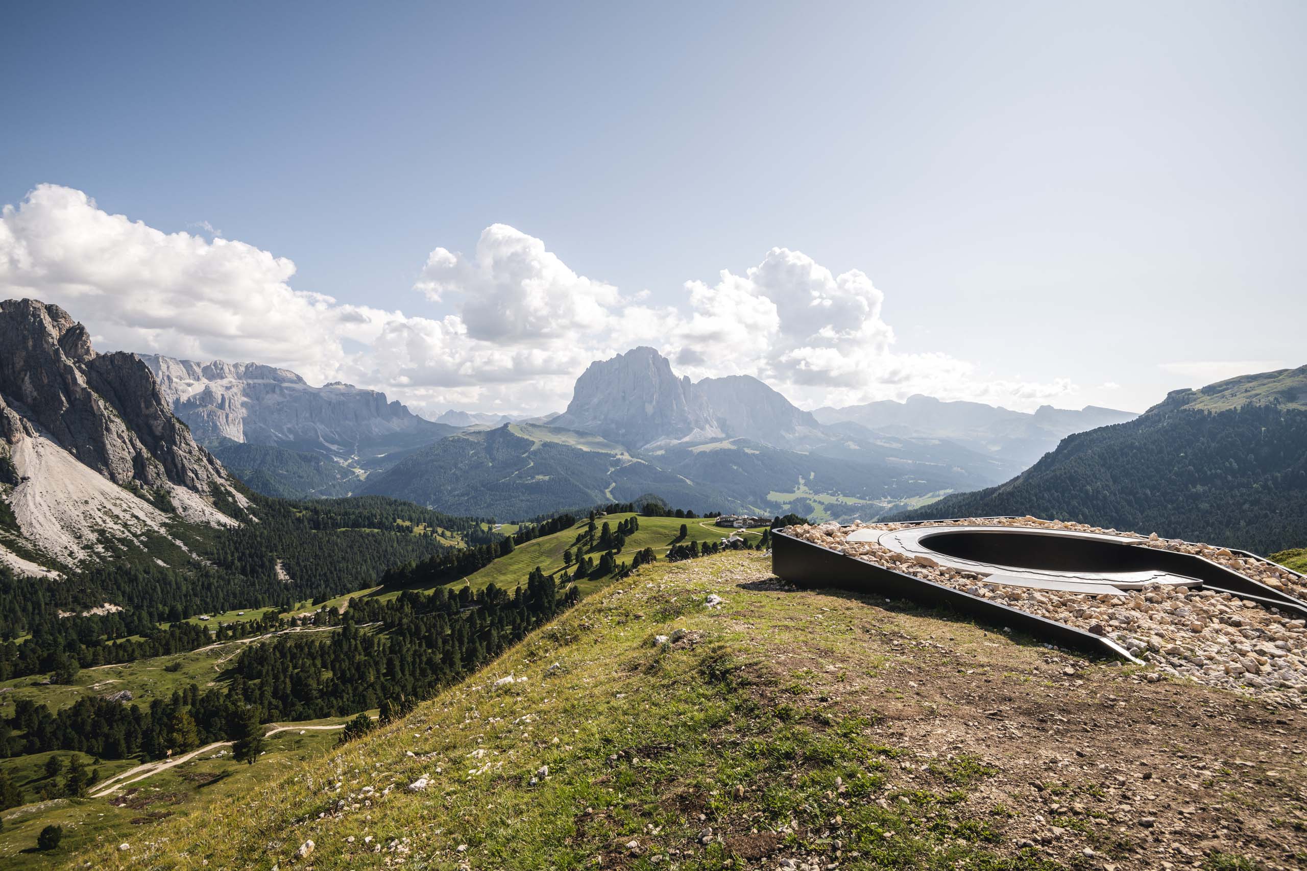 Deine Unterkunft in St. Christina im Grödnertal: Willkommen! Berglandschaft mit Felsen, Wiesen und Wolken am Himmel